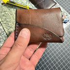 The Buccaneer held over the workbench, navy stitching down one edge